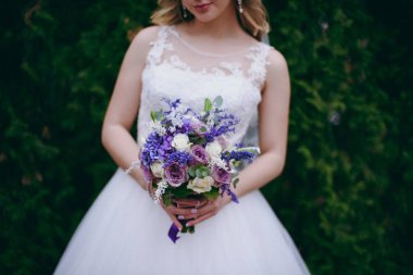 Gelin düğün töreninde büyük bir buket tutuyor.