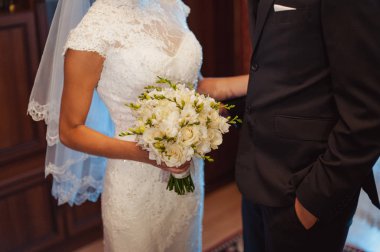 Gelin düğün töreninde büyük bir buket tutuyor.