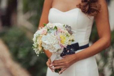 Gelin düğün töreninde büyük bir buket tutuyor.