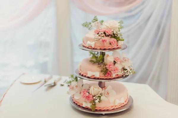 Прекрасный белый и цветной свадебный торт. Жених и невеста режут свадебный торт — стоковое фото