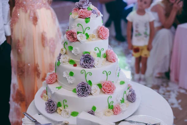 Vackra vita och färgade bröllopstårta. En brud och en brudgum skär sin bröllopstårta — Stockfoto