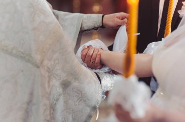 Gelin ve damadın elleri düğün havlularını bağladı. Rahip gelinin el havlusunu bağlar. Kilisedeki genç çiftlerin elleri. Kilise töreninde el ele tutuşan çift. Düğün günü..