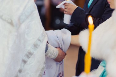 Gelin ve damadın elleri düğün havlularını bağladı. Rahip gelinin el havlusunu bağlar. Kilisedeki genç çiftlerin elleri. Kilise töreninde el ele tutuşan çift. Düğün günü..