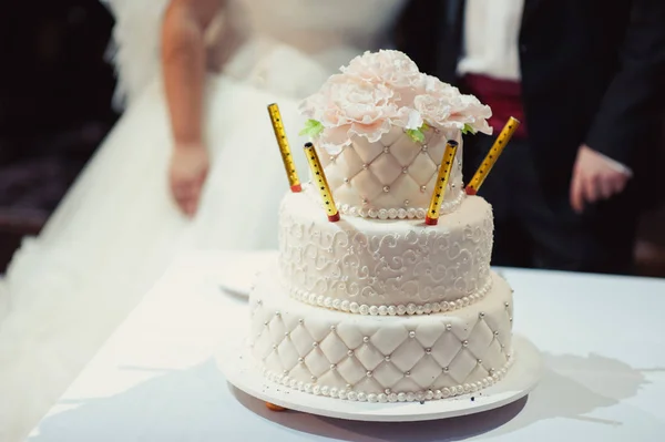 Beautiful white and colored wedding cake. A bride and a groom is cutting their wedding cake — Stock Photo, Image