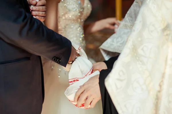 新娘和新郎的手绑着婚纱.牧师把新娘的手巾捆起来.教堂里的年轻夫妇的手。在教堂的仪式上，夫妻手牵手。婚礼日. — 图库照片
