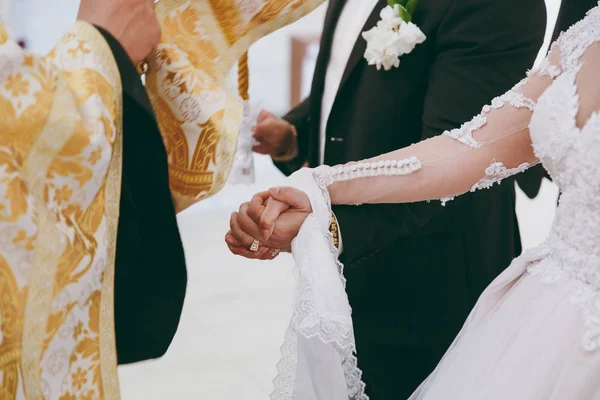 Gelin ve damadın elleri düğün havlularını bağladı. Rahip gelinin el havlusunu bağlar. Kilisedeki genç çiftlerin elleri. Kilise töreninde el ele tutuşan çift. Düğün günü..