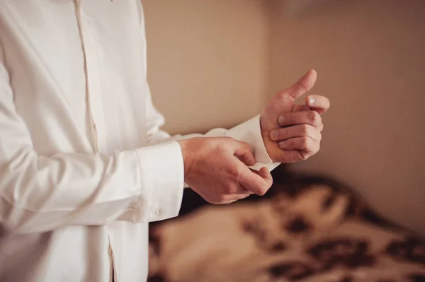 De bruidegom vastmaakt de cufflink op het shirt mouw close-up — Stockfoto