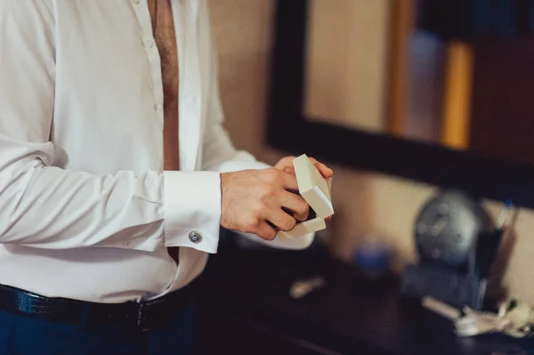 The groom fastens the cufflink on the shirt sleeve close-up — Stock Photo, Image