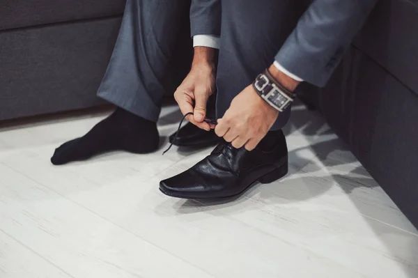 The man wears shoes. Tie the laces on the shoes. Men\'s style. Professions. To prepare for work, to the meeting.