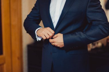 Zarif Damat Düğün ceketli beyaz gömlek ve turkuaz kravat takıyor. Mavi takım damadın elleri.