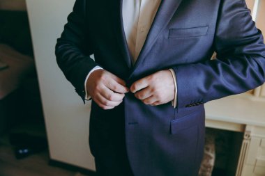 Zarif Damat Düğün ceketli beyaz gömlek ve turkuaz kravat takıyor. Mavi takım damadın elleri.