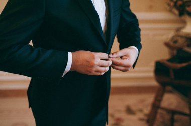 Zarif Damat Düğün ceketli beyaz gömlek ve turkuaz kravat takıyor. Mavi takım damadın elleri.