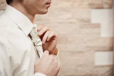 Damat takım elbiseli bir kravat düzeltir. Damat aksesuarları