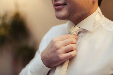 Damat takım elbiseli bir kravat düzeltir. Damat aksesuarları