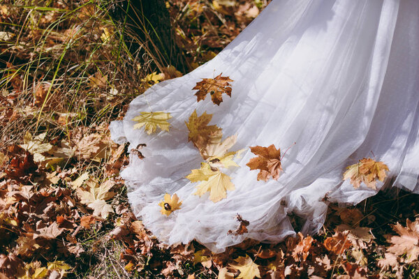 Yellow leaves on a wedding dress in autumn