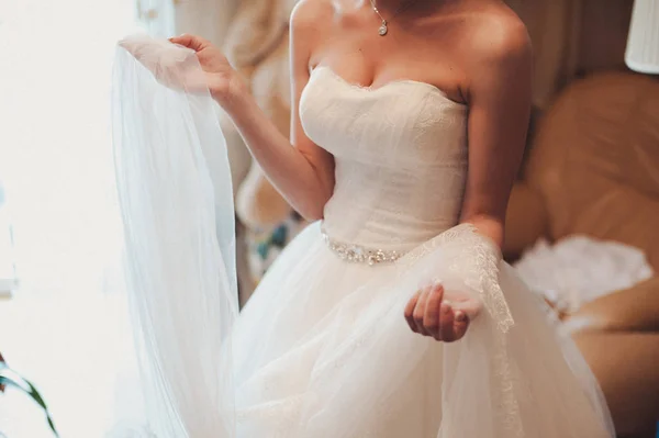Módní družičky šaty pomáhal nosit luk na zadní svatební šaty nevěsty. Svatební den ráno. — Stock fotografie