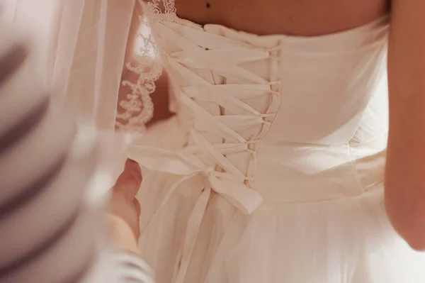 Vestidos de damas de honra na moda ajudou a usar o arco na parte de trás da noiva vestido de noiva. Dia do casamento da manhã . — Fotografia de Stock