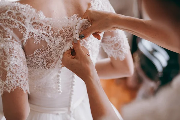 Vestidos de damas de honra na moda ajudou a usar o arco na parte de trás da noiva vestido de noiva. Dia do casamento da manhã . — Fotografia de Stock