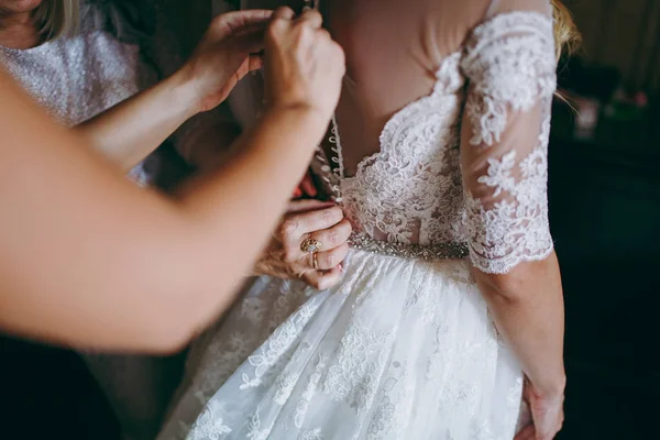 फैशनेबल दुल्हनों के कपड़े शादी की पोशाक दुल्हन की पीठ पर धनुष पहनने में मदद की। सुबह शादी का दिन . — स्टॉक फ़ोटो, इमेज