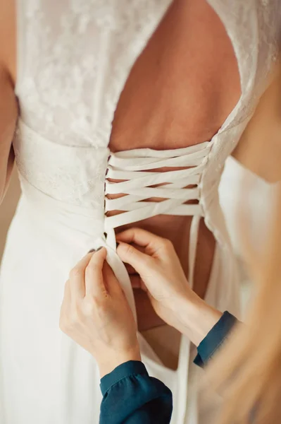 Fashionable bridesmaids dresses helped wear bow on back of wedding dress bride. Morning wedding day.