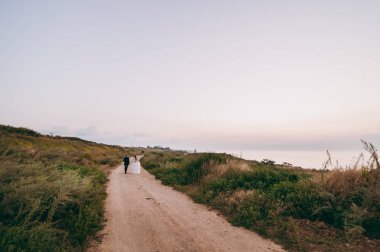 Kum bir yürüyüş gelin ve damat deniz alanı günbatımı mimari düğün çift çimen