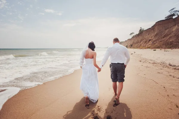 Svatební pár na procházka nevěsta a ženich moře pole slunce architektuře trávy písek — Stock fotografie