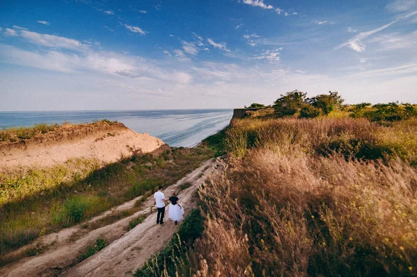 Boda pareja en un paseo novia y novio mar campo puesta del sol arquitectura hierba arena —  Fotos de Stock