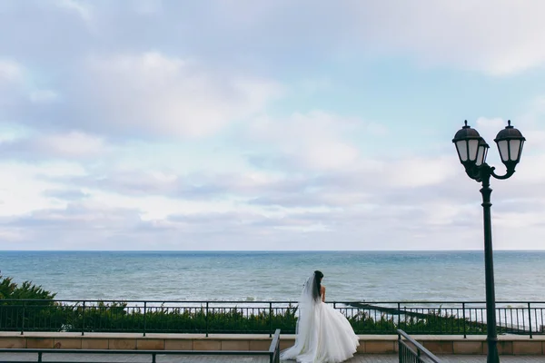 Couple de mariage sur une promenade mariée et marié champ de mer coucher de soleil architecture herbe sable — Photo