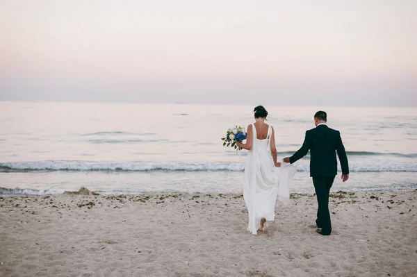 Wedding couple on a walk bride and groom sea field sunset architecture grass sand — Stock Photo, Image
