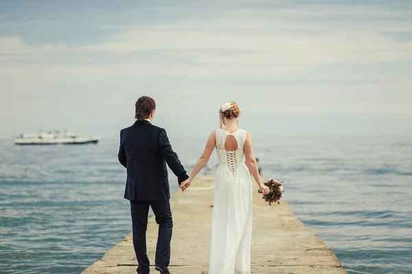 Casamento casal em um passeio noiva e noivo mar campo pôr do sol arquitetura grama areia — Fotografia de Stock