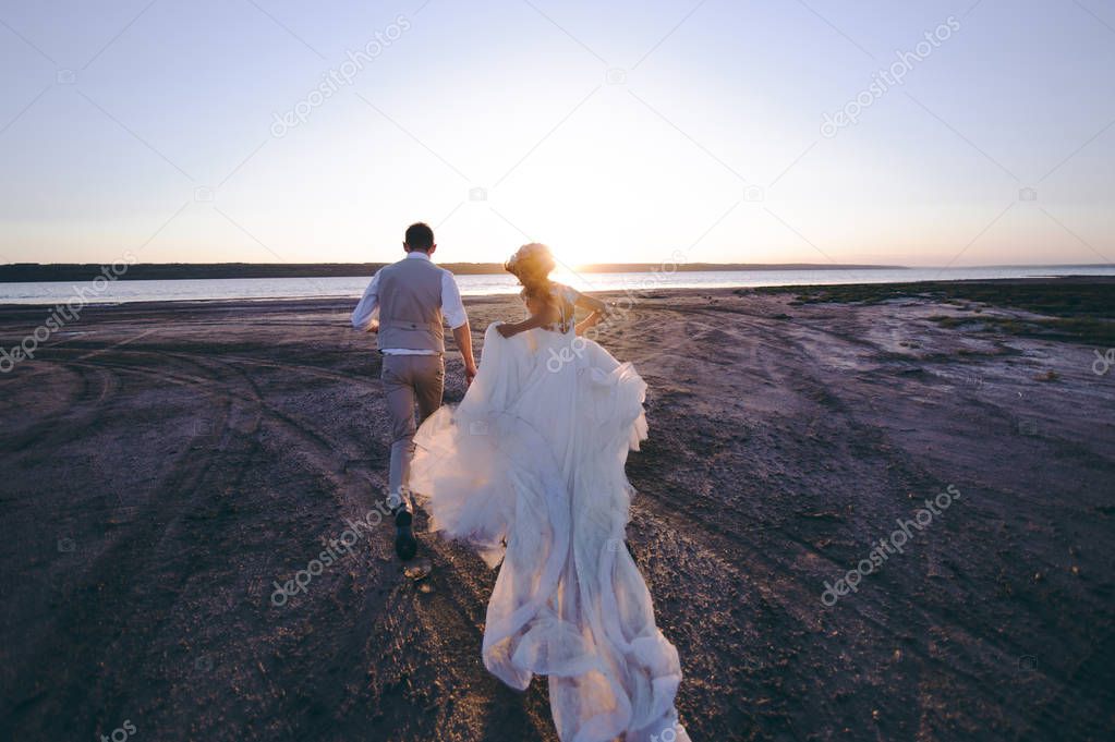 Wedding couple on a walk bride and groom sea field sunset architecture grass sand
