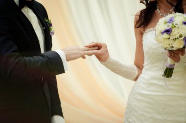 Halkaları koyarak. Gelin ve damat yüzük elbise