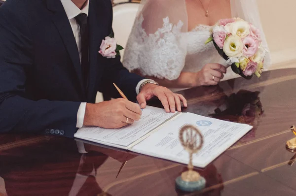 Τελετή υπογραφής. Η νύφη και ο γαμπρός να υπογράψετε τα έγγραφα σχετικά με το γάμο — Φωτογραφία Αρχείου