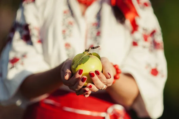 Una ragazza in un ricamo tiene una mela tra le mani — Foto Stock