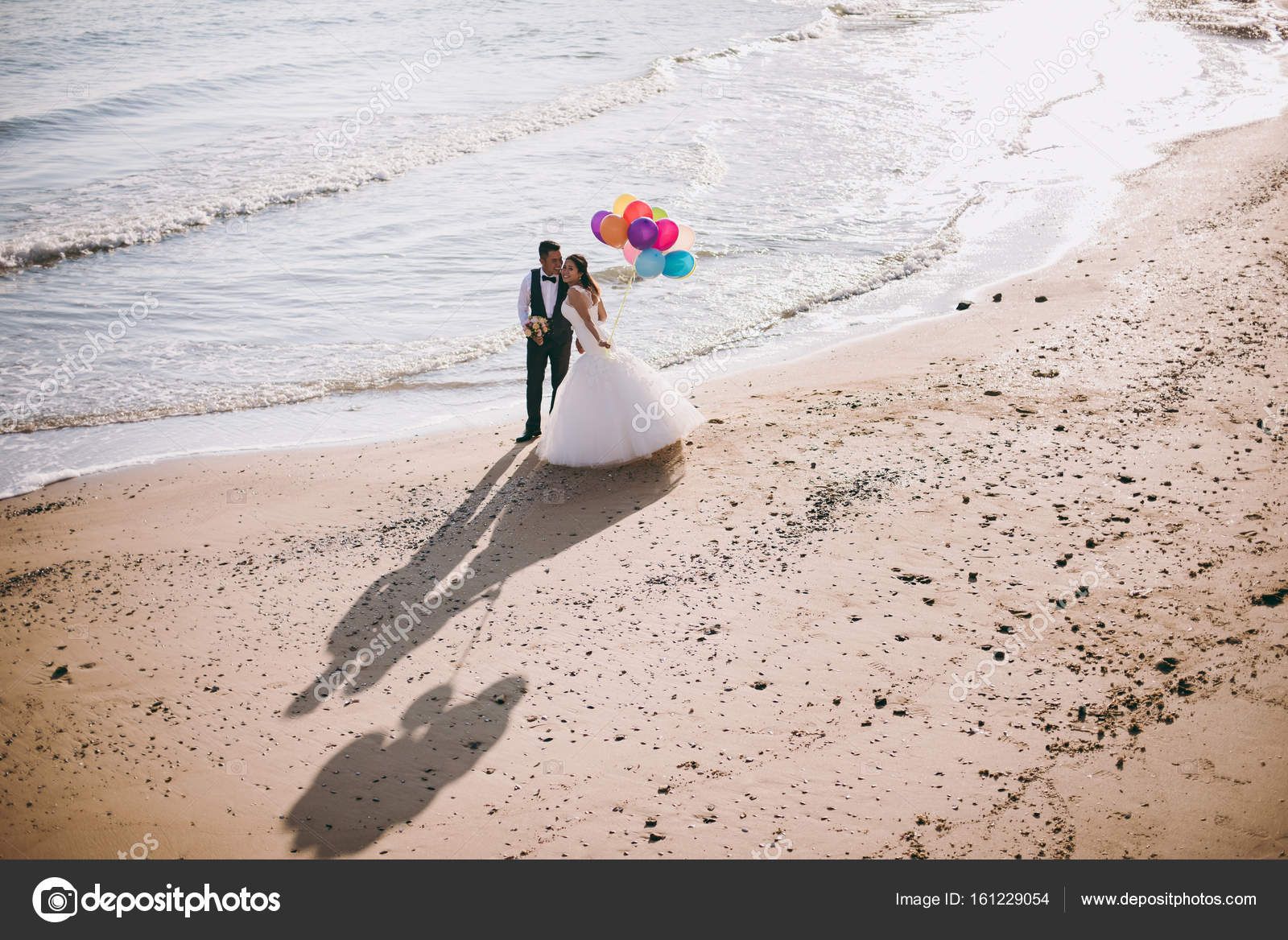 Wedding Couple With Balls Walking Along The Seashore Stock