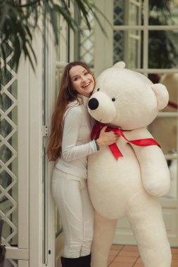 Büyük beyaz oyuncak ayı tutan güzel kız