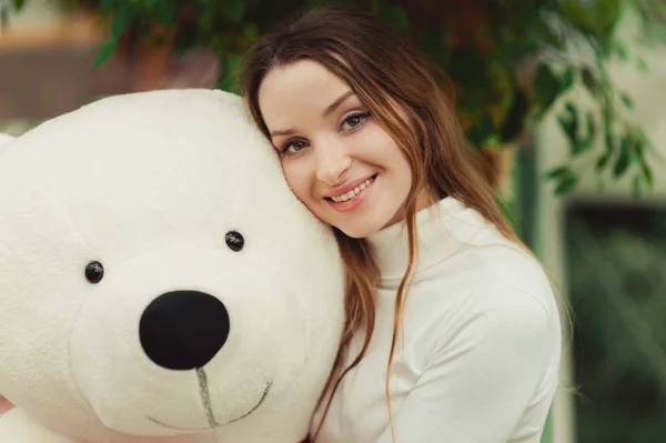 Bella ragazza che tiene un grande orsacchiotto bianco — Foto Stock