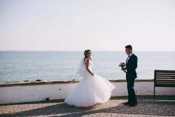 Pareja de boda en un paseo por el terraplén cerca del mar — Foto de Stock