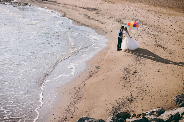 Ζευγάρι γάμο με μπάλες περπάτημα κατά μήκος της ακτής — Φωτογραφία Αρχείου