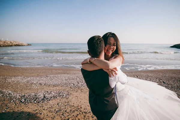Pareja de bodas paseando por la playa cerca del mar —  Fotos de Stock