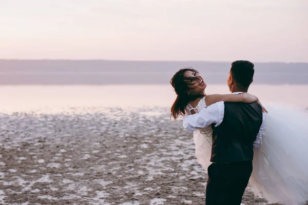 河口の海岸に沿って歩く結婚式のカップル — ストック写真