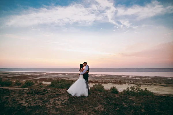 河口の海岸に沿って歩く結婚式のカップル — ストック写真