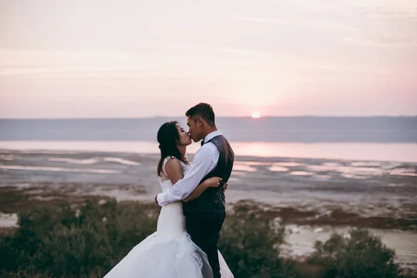 Pareja de boda caminando a lo largo de la orilla del estuario —  Fotos de Stock