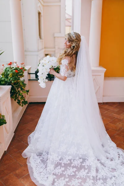 Vackra lockiga blonda bruden med en bukett blommor — Stockfoto