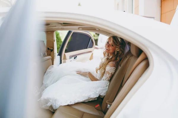 Beautiful blond bride gets into the car — Stock Photo, Image