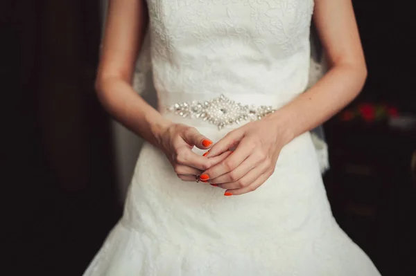 Mãos da noiva com manicure laranja no vestido — Fotografia de Stock