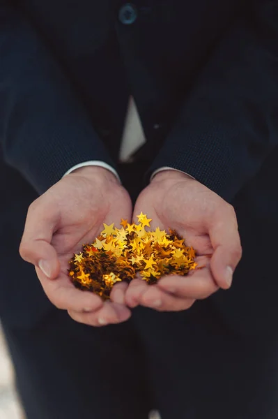 Mann hält goldene Konfettisterne in der Hand — Stockfoto