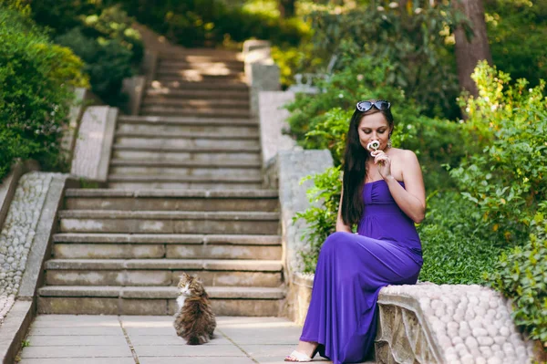 Ragazza in abito viola e gatto di strada — Foto Stock