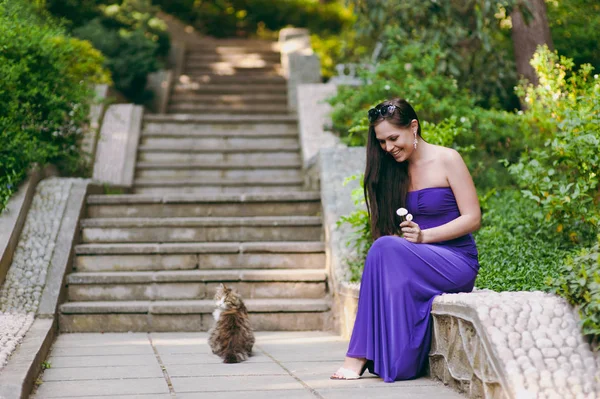 Ragazza in abito viola e gatto di strada — Foto Stock