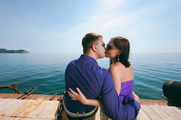 Um casal amoroso em roupas roxas na costa — Fotografia de Stock